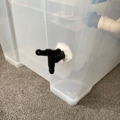 a plastic container with a black handle and white toilet paper in it on the floor