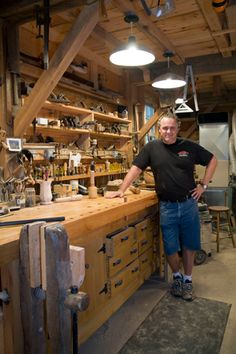 a man standing in front of a wooden workbench filled with tools and supplies