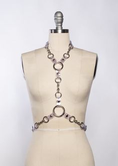 The Industrial Chained Harness pairs PVC and metal hardware together, showcasing it in a way that allows it to stand out and be the main event.Buckles at neck and waist.Chains and o-rings are linked together with black PVC. Because of the oversized hardware, this piece has a nice weight to it.Silver toned industrial hardware. On-model photo shows this harness in clear PVC layered with the Industrial Draped Chain Set.Custom sizing available. All pieces are MADE TO ORDER, standard sizes XS-XXL or Metal Body Chain With Chain Strap For Festivals, Silver Adjustable Body Chain For Festivals, Metal Body Jewelry With Chain Strap For Festivals, Festival Body Jewelry With Metal Chain Strap, Metal Chain Body Jewelry For Festivals, Metal Adjustable Body Chain For Festivals, Silver Chain Metal Body Jewelry For Festivals, Festival Silver Chain Body Jewelry, Edgy Silver Body Jewelry For Festivals