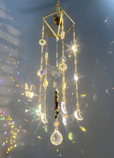 a gold and crystal wind chime hanging from the ceiling with sun shining through it