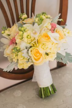 a bouquet of flowers sitting on top of a table in front of a wooden chair