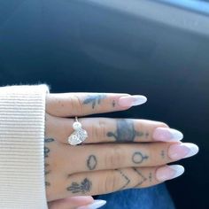 a woman's hand with tattoos and a ring on her left wrist, sitting in the back seat of a car