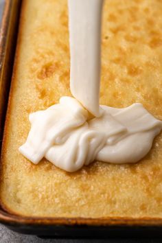 a person is spreading icing on top of a cake in a baking pan with a spatula