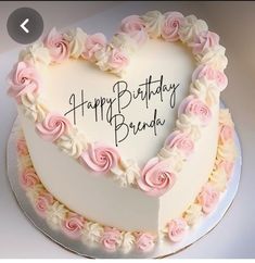 a heart shaped birthday cake with pink and white frosting roses in the shape of a heart