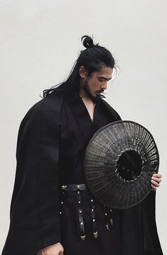 a man dressed in black holding a fan