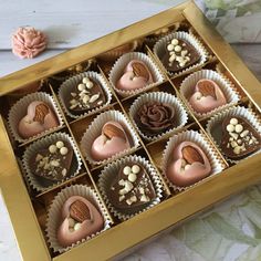 a box filled with lots of chocolates on top of a wooden table next to a flower