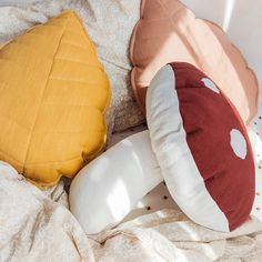 three pillows sitting on top of a bed next to an orange and white pillow cover