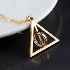 a gold necklace with an open triangle and two interlocked circles in the middle