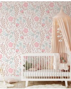 a white crib in front of a floral wallpaper