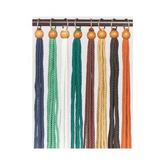 an assortment of different colored cords hanging from a hook on a white wall with pumpkins in the background