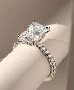 an engagement ring with a princess cut diamond surrounded by pave set round brilliant diamonds