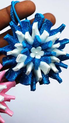 two different colored hair clips in the palm of someone's hand, one with blue and white flowers on it