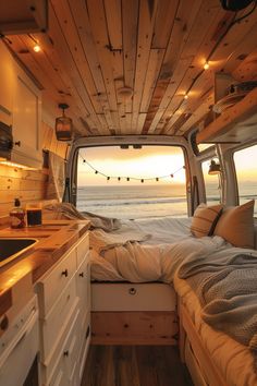 the inside of a camper van with a bed in it and lights hanging from the ceiling