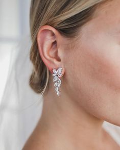 a close up of a woman wearing earrings with flowers on it's ear and the back of her head