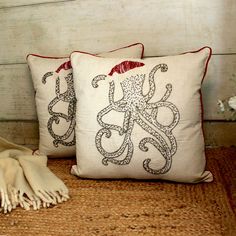 two pillows with an octopus on them sitting on a bed next to a throw pillow