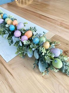 an arrangement of fake eggs and greenery on a table