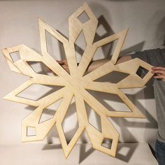 a person holding up a wooden snowflake