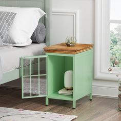 a small green table with a wooden top in a bedroom next to a bed and window