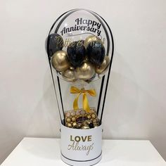 a vase filled with balloons and chocolates on top of a white table next to a sign that says happy anniversary