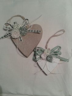 two heart shaped tags with bows on them sitting on top of a piece of paper