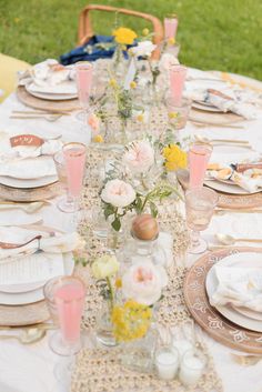 the table is set with flowers and plates on it for an outdoor dinner or brunch