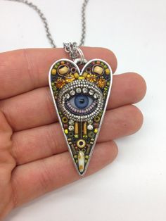 a hand holding a necklace with an eye in it