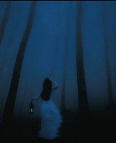 a person standing in the dark with a lantern on their head and trees behind them