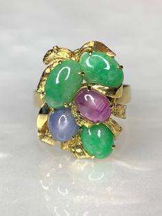 Jade Ring, Jade Rings For Women, Jade Ring Gold, Vintage Gemstone Ring, Star Sapphire Ring, Cabochon Ring, Bouquet Ring, Multi Stone Ring A multi colored gemstone bouquet ring with solid 14k gold leaf/ petal detailing. Featuring 3 oval shaped genuine green jade stones along with a single round star sapphire and a single oval star ruby. *Approximate ring weight: 6.36 grams *Ring size: US 7 1/2 * Complimentary resizing is available up to 3 sizes larger or smaller than stated size. Multicolor Cabochon Rings Fine Jewelry, Multicolor Cabochon Rings In Fine Jewelry Style, Multicolor Cabochon Rings For Anniversary, Heirloom Multi-stone Oval Cabochon Rings, Unique Oval Multi-stone Emerald Ring, Green Multi-stone Oval Cabochon Jewelry, Jade Rings For Women, Ring Bouquet, Bouquet Ring