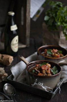 two bowls filled with food sitting on top of a table next to a bottle of wine