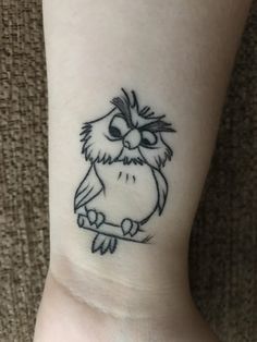 an owl tattoo on the wrist is shown in black and grey ink, with one eye open