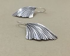 "These whimsical silver earrings are inspired by the delicate wings of a moth. The sterling silver wings are engraved with gentle striations and gently curved. They are suspended from a hand-formed sterling silver ear wire with an overall length of about 1 3/4\" (4.4cm) Your earrings will be made specially for you when you order. Due to the nature of the technique used in making the earrings, each one will be a little different from the pair in the photos, making them singularly yours.  All purc Handmade Silver Wing-shaped Earrings, Winged Sterling Silver Earrings For Gift, Winged Sterling Silver Earrings In Silver, Winged Sterling Silver Earrings As Gift, Sterling Silver Winged Earrings Gift, Silver Winged Sterling Silver Earrings, Silver Sterling Silver Winged Earrings, Earrings Boho Chic, Moth Wings