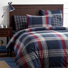 a bed with blue and red plaid comforter in a bedroom next to a night stand