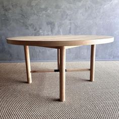 a round wooden table sitting on top of a carpeted floor next to a wall