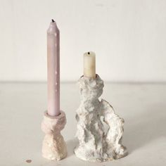 a candle holder with a small white dog next to it and a smaller pink pillar