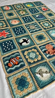 a crocheted blanket with fish and other sea creatures on it, sitting on a bed