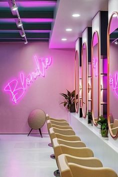 there are many chairs in the room with neon signs on the wall and mirrors behind them