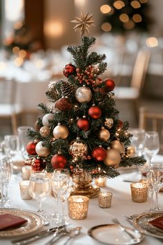 a small christmas tree sitting on top of a table next to glasses and silverware