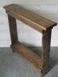 a wooden bench sitting on top of a carpeted floor next to a white wall