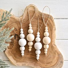 three wooden beads hanging from strings on a piece of wood next to a pine tree