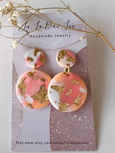 two pink and gold earrings on top of a card