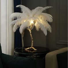 a white palm tree lamp on a black table in front of a window with curtains