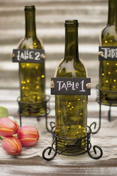 three wine bottles with labels on them sitting on a table next to tulips