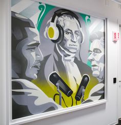 a large painting with headphones hanging on the wall next to a pair of microphones