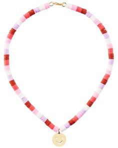 a red, white and pink necklace with a gold smiley face charm on it's end