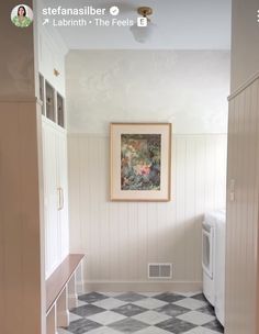 an empty room with a checkered tile floor and white walls, framed artwork on the wall