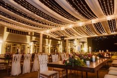 the inside of a wedding venue with white drapes and string lights