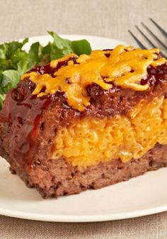 a piece of meatloaf on a plate with lettuce and a fork