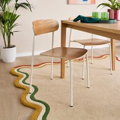 two wooden chairs sitting on top of a rug next to a table with potted plants