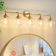 a bathroom vanity with three lights and a mirror on the wall next to potted plant