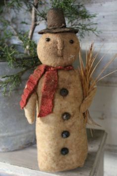 a stuffed snowman is sitting on a shelf next to a potted plant and some branches